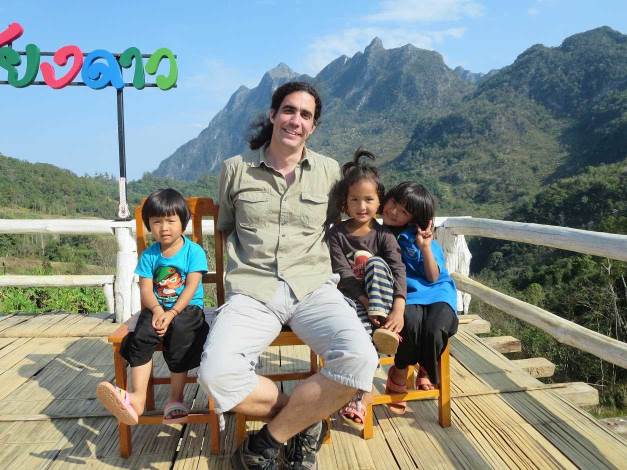 Sebastian sitting on a bench with 3 Thai children